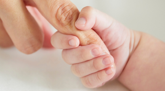 Manó de bebé agarrando la mano de su madre